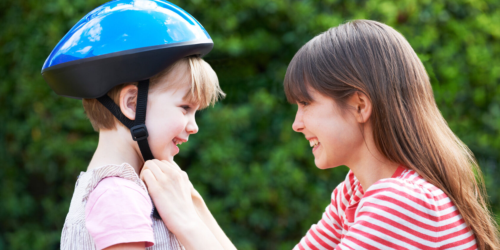 Young Woman Putting Cycle Helmet Onto Girl